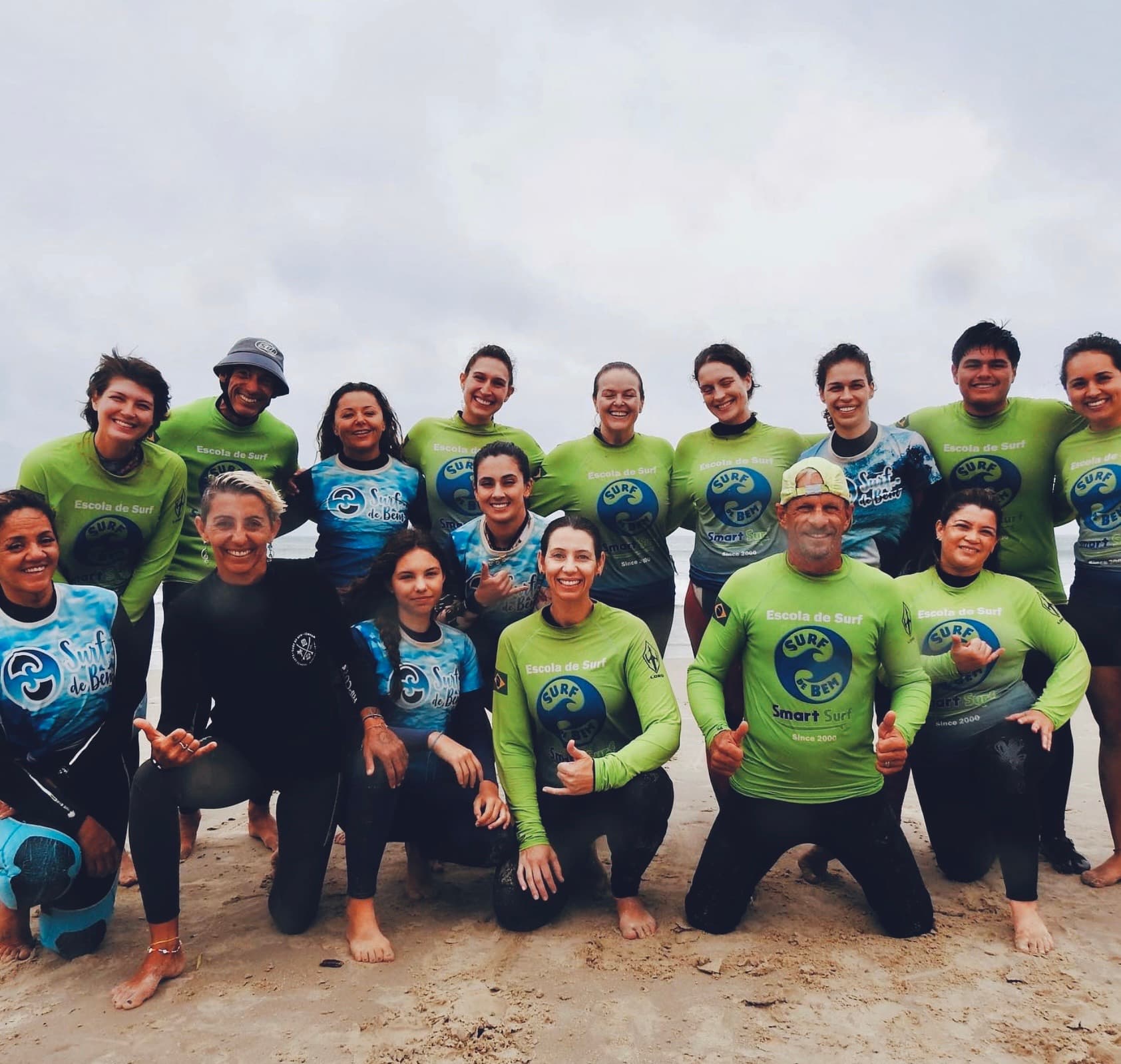 Grande grupo com camisas da Surf de Bem, reunido e sorrindo na praia.